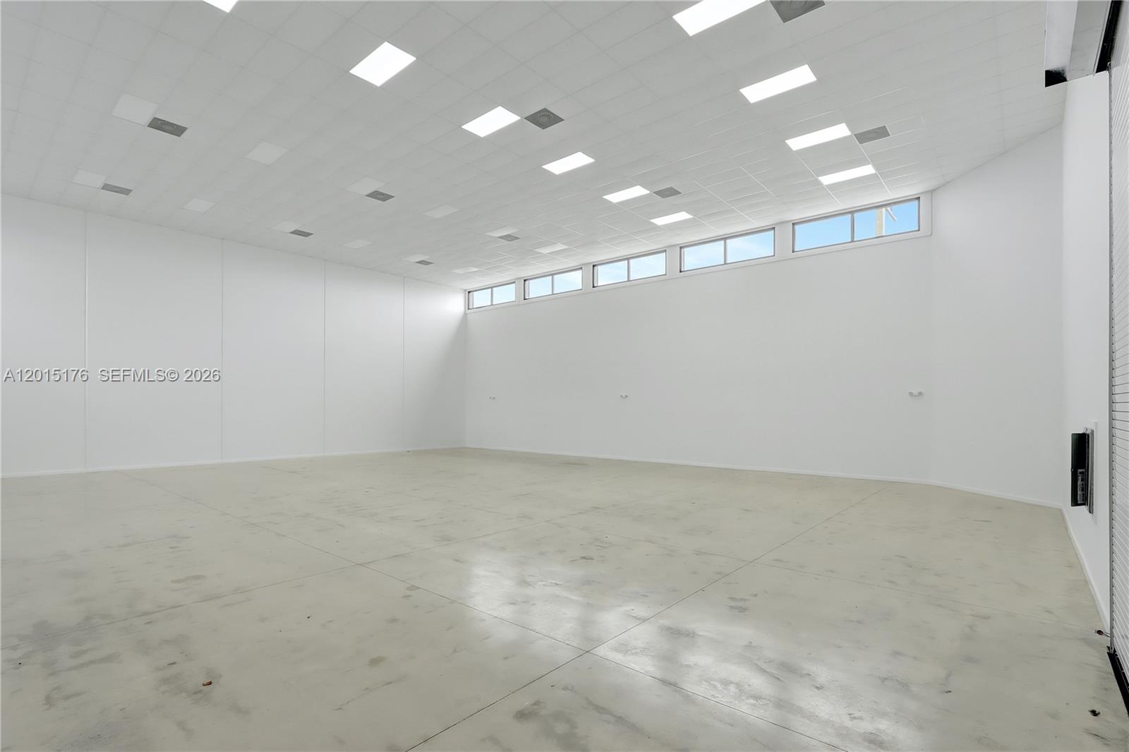 An empty, white-walled commercial warehouse space features a high drop ceiling and concrete flooring — 6767 NE 2nd ave, Miami FL 33138, MIAMI, FL