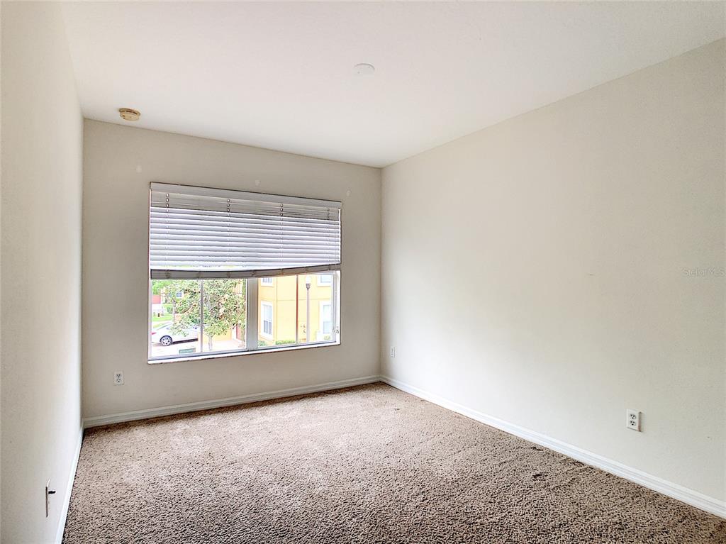 An empty bedroom features beige walls, brown carpeting, and a window with white blinds — 3660 IDITAROD LANE, ORLANDO, FL