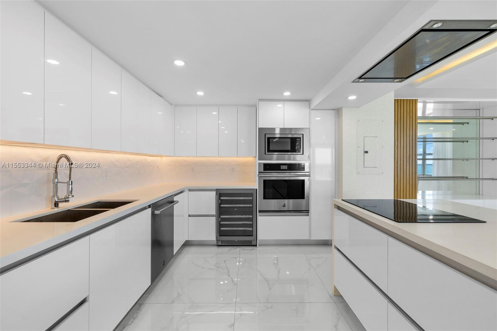 A modern white kitchen features sleek cabinetry, stainless steel appliances, and marble-look tile flooring — 5151 Collins Ave # 1527, Miami Beach FL 33140, MIAMI BEACH, FL