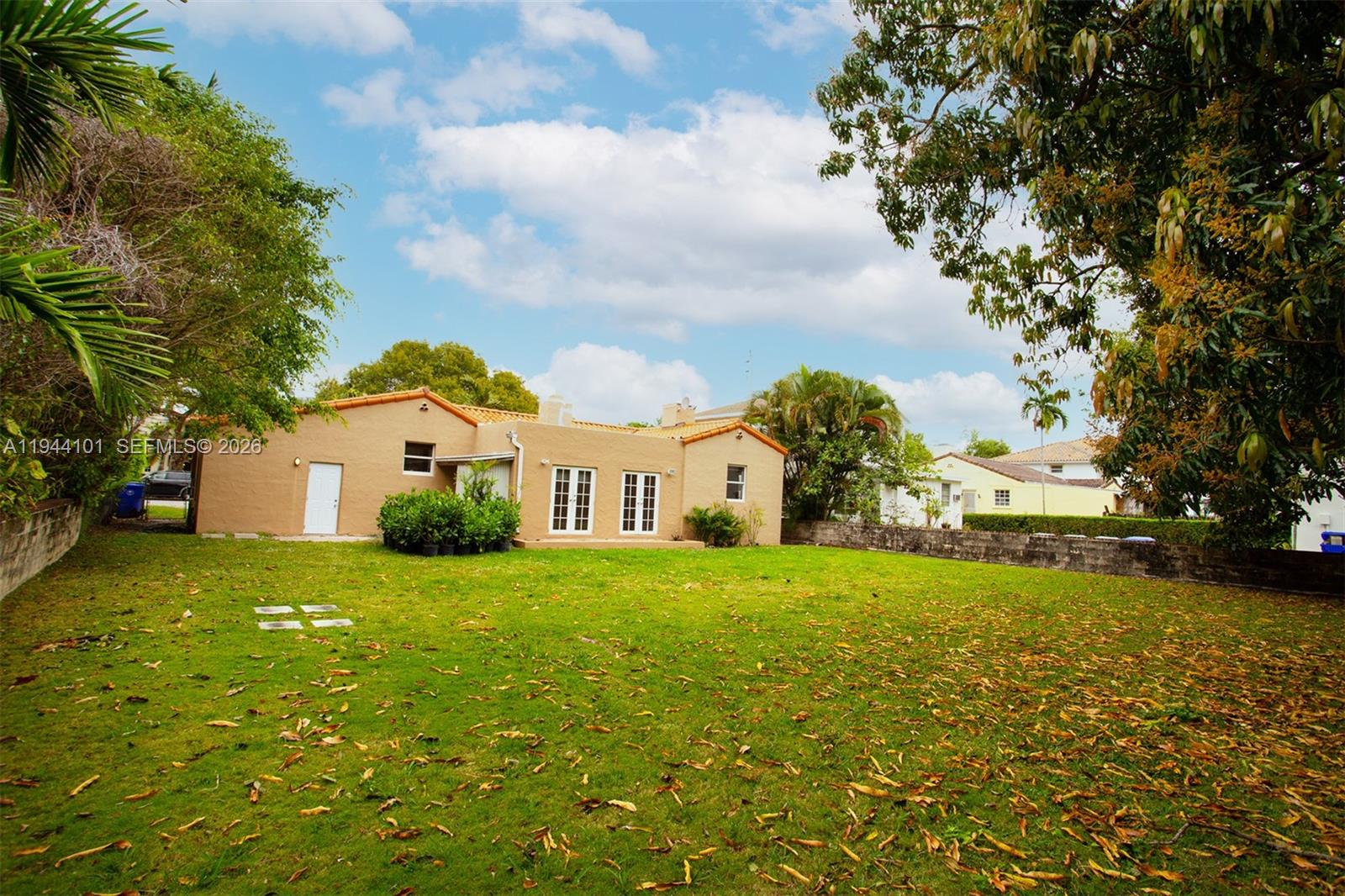 The exterior of a tan stucco house features a large backyard with scattered leaves — 236 SW 28th Rd, Miami FL 33129, MIAMI, FL