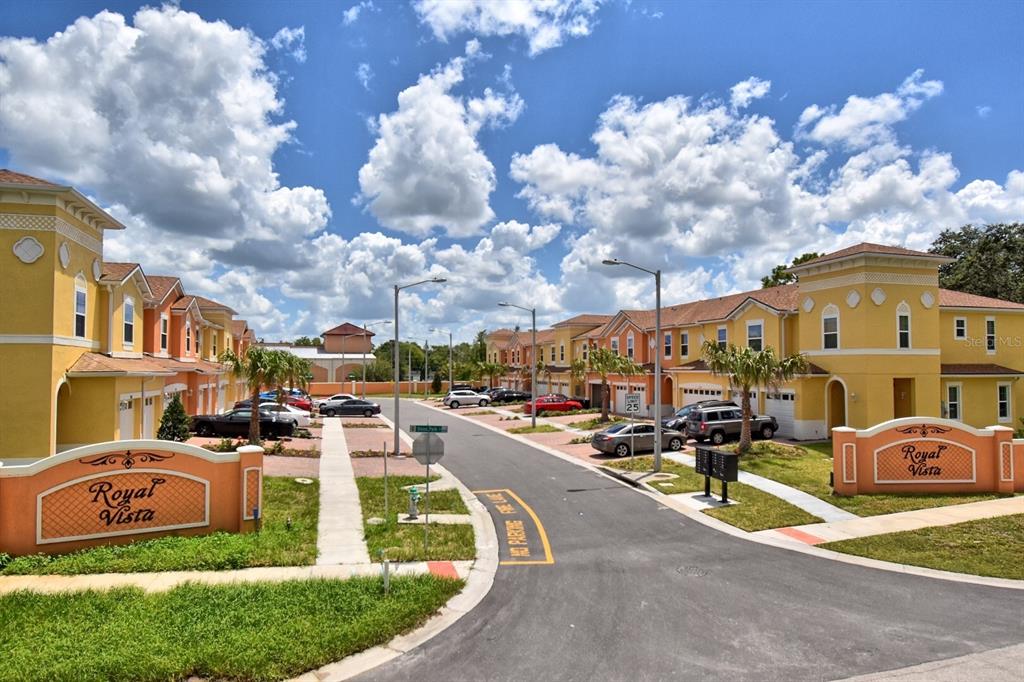 An exterior view of a residential complex with yellow townhomes and two Royal Vista signs — 2036 ROYAL VISTA COURT, ORLANDO, FL