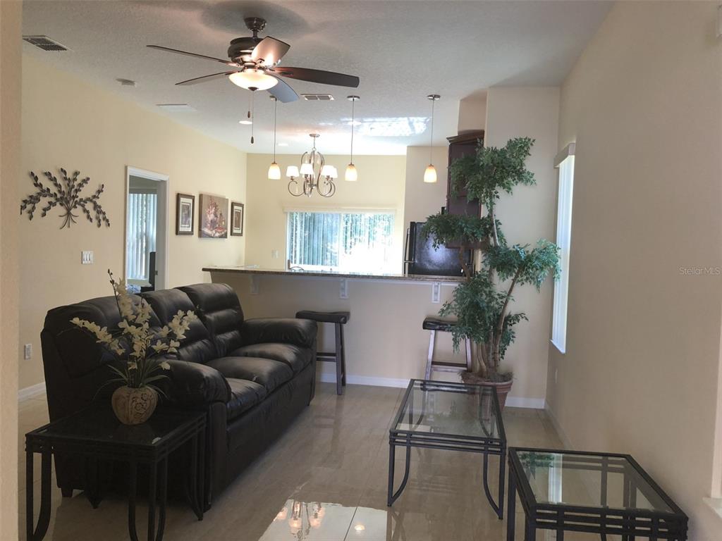 A living room with a black leather sofa, glass tables, and a breakfast bar counter — 2036 ROYAL VISTA COURT, ORLANDO, FL