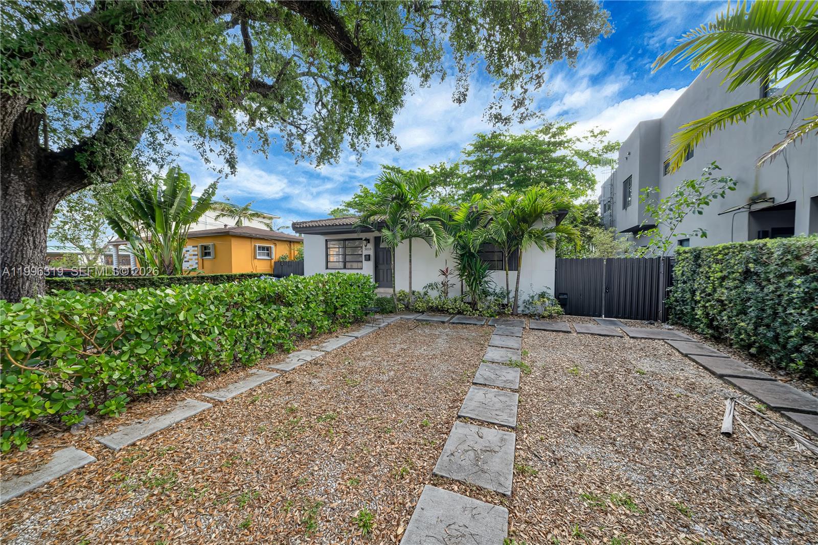A white house with a gravel driveway and stone pavers sits behind a green hedge — 3033 Hibiscus St, Miami FL 33133, MIAMI, FL