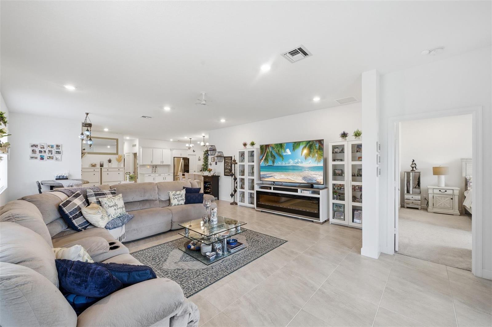 A spacious living room features a large sectional sofa, a television, and tile flooring — 1279 Tangled Orchard Trace # 1279, Loxahatchee FL 33470, LOXAHATCHEE, FL
