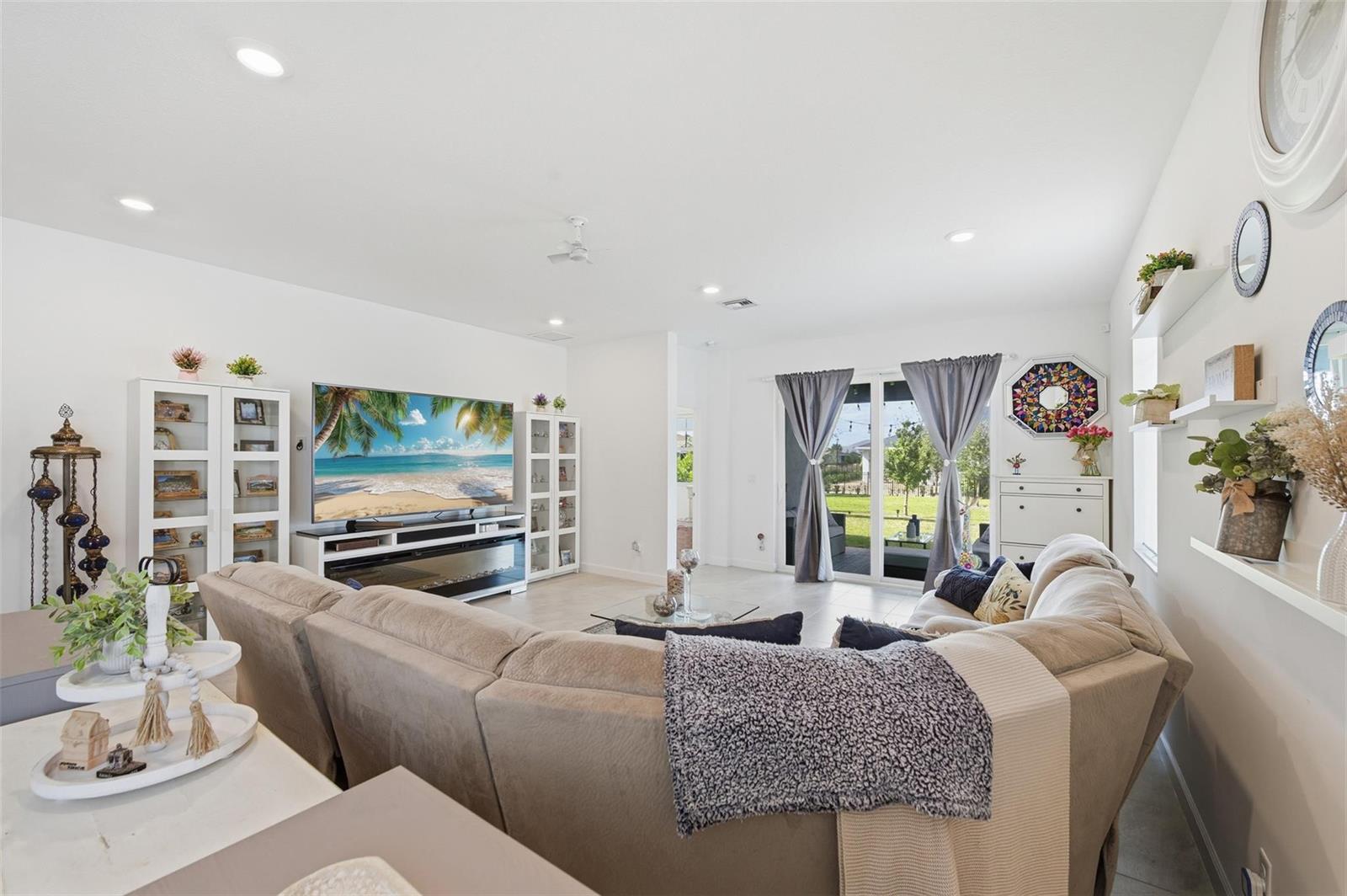 A living room features a large sectional sofa, a television, and sliding glass patio doors — 1279 Tangled Orchard Trace # 1279, Loxahatchee FL 33470, LOXAHATCHEE, FL
