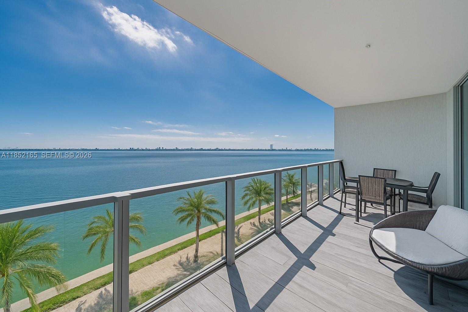 A balcony with gray wood-look flooring overlooks a body of water and palm trees — 2900 NE 7th Ave # 405, Miami FL 33137, MIAMI, FL