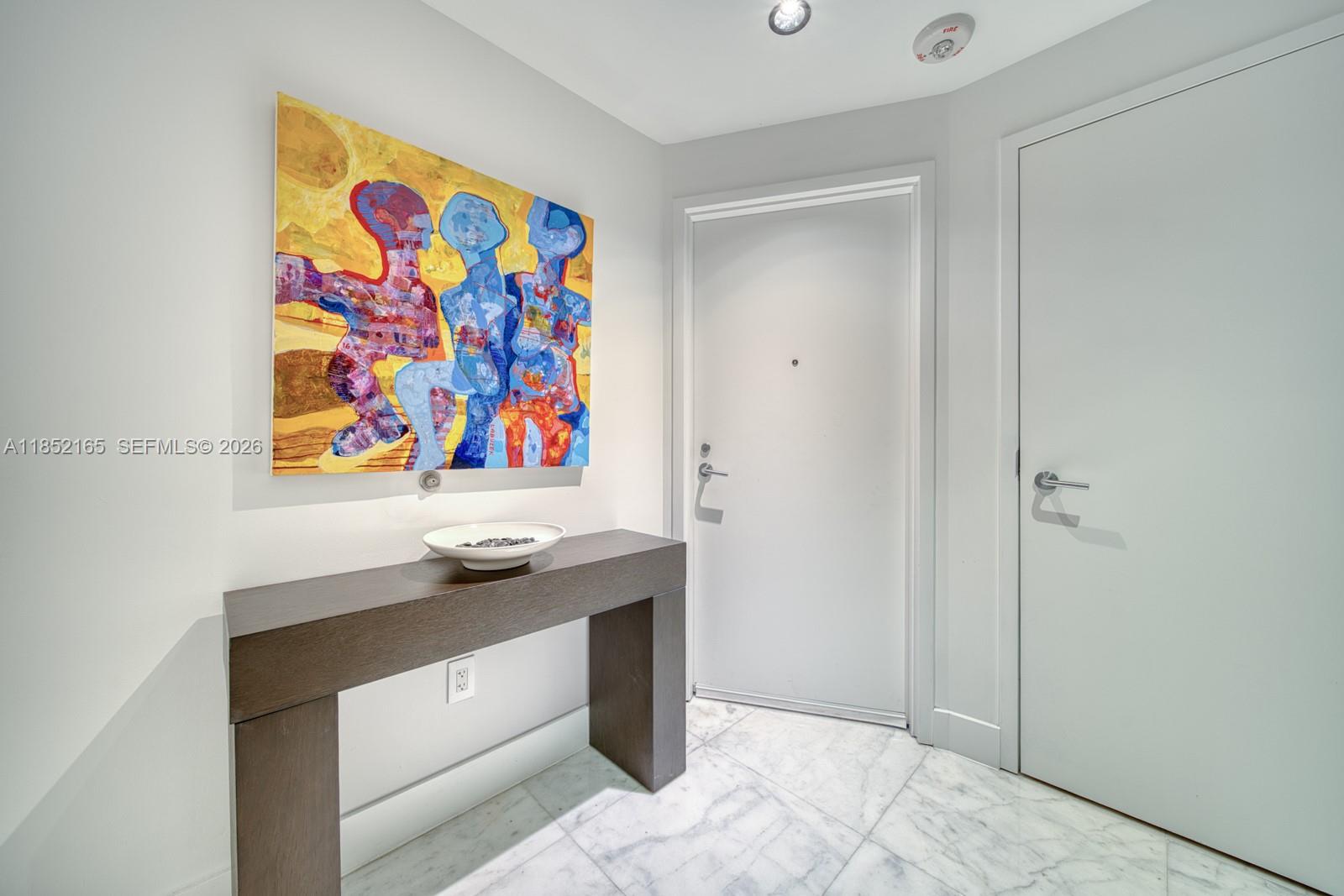 A modern entryway features a dark wood console table, abstract wall art, and marble flooring — 2900 NE 7th Ave # 405, Miami FL 33137, MIAMI, FL