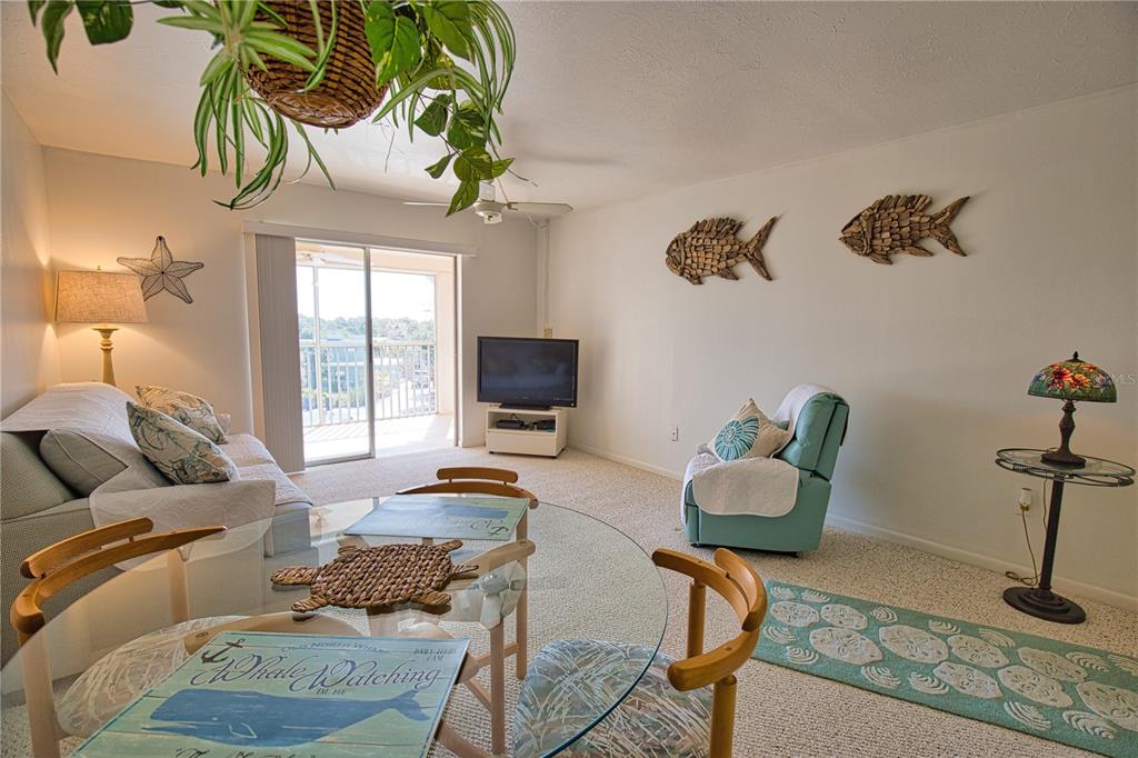 A living and dining area features coastal decor, a glass table, and a sliding glass door — 200 N THE ESPLANADE UNIT C-9, VENICE, FL