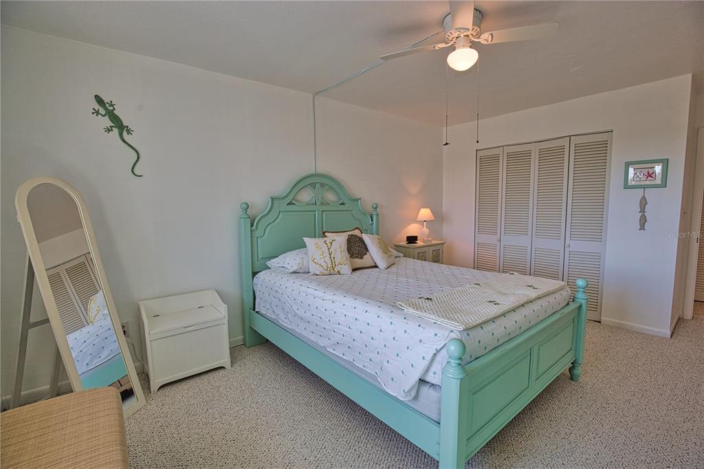 A bedroom features a light green bed frame, a floor mirror, and a ceiling fan — 200 N THE ESPLANADE UNIT C-9, VENICE, FL