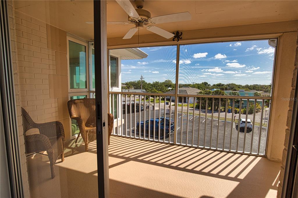 A screened-in balcony features two wicker chairs, a ceiling fan, and a view of parking — 200 N THE ESPLANADE UNIT C-9, VENICE, FL