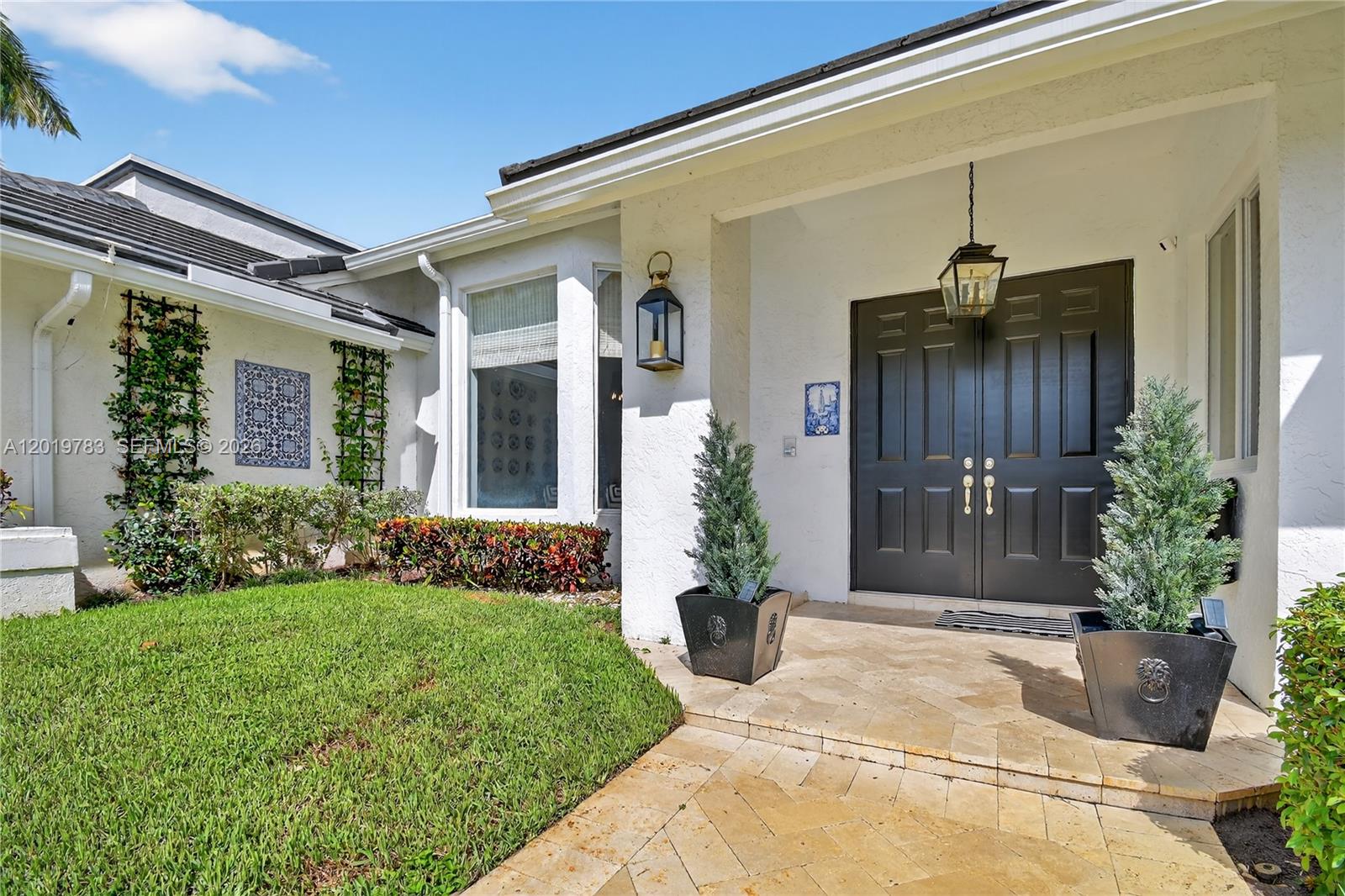 A white house exterior features a dark double front door, stone patio, and potted plants — 4431 Bocaire Boulevard, Boca Raton FL 33487, BOCA RATON, FL