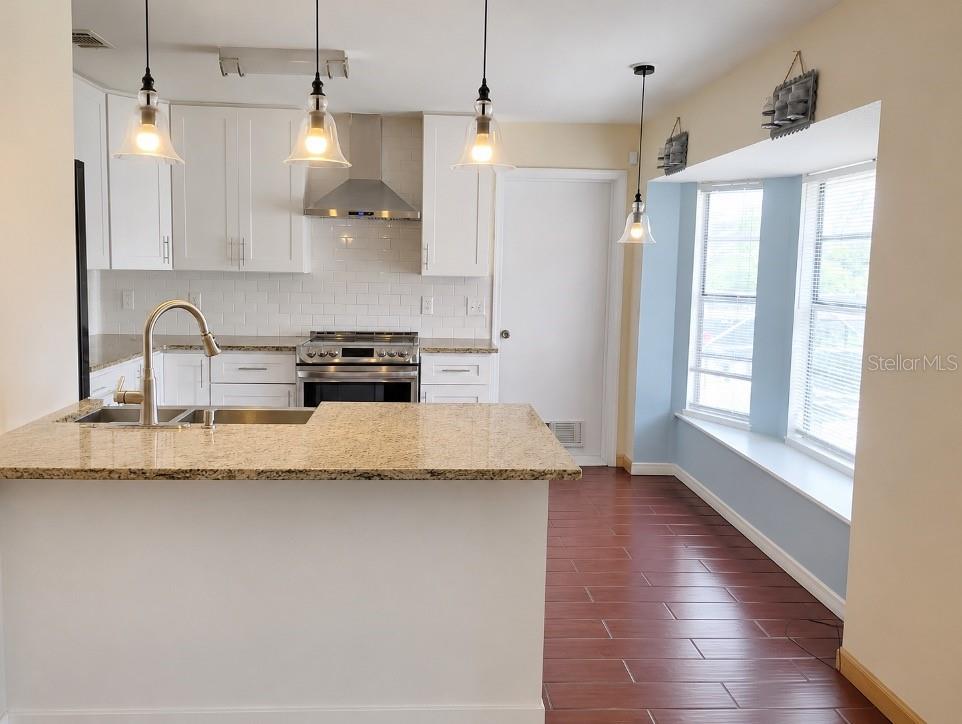 A kitchen features white cabinets, granite countertops, stainless steel appliances, and a bay window area — 9120 QUEEN ELIZABETH COURT, ORLANDO, FL