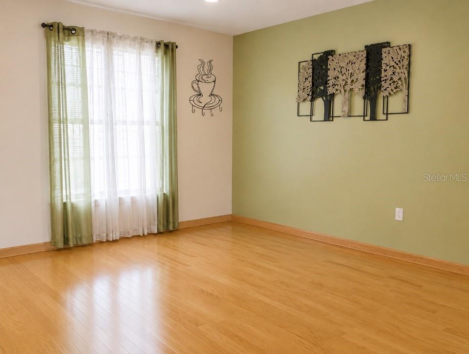 A room with light wood flooring, green walls, a window with curtains, and wall decor — 9120 QUEEN ELIZABETH COURT, ORLANDO, FL