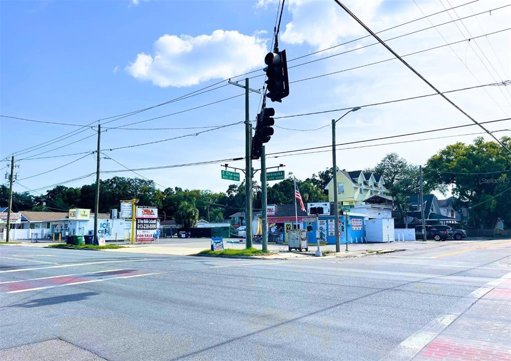 An intersection features a traffic light, street signs, and small commercial buildings under a blue sky — 4330 N NEBRASKA AVENUE, TAMPA, FL