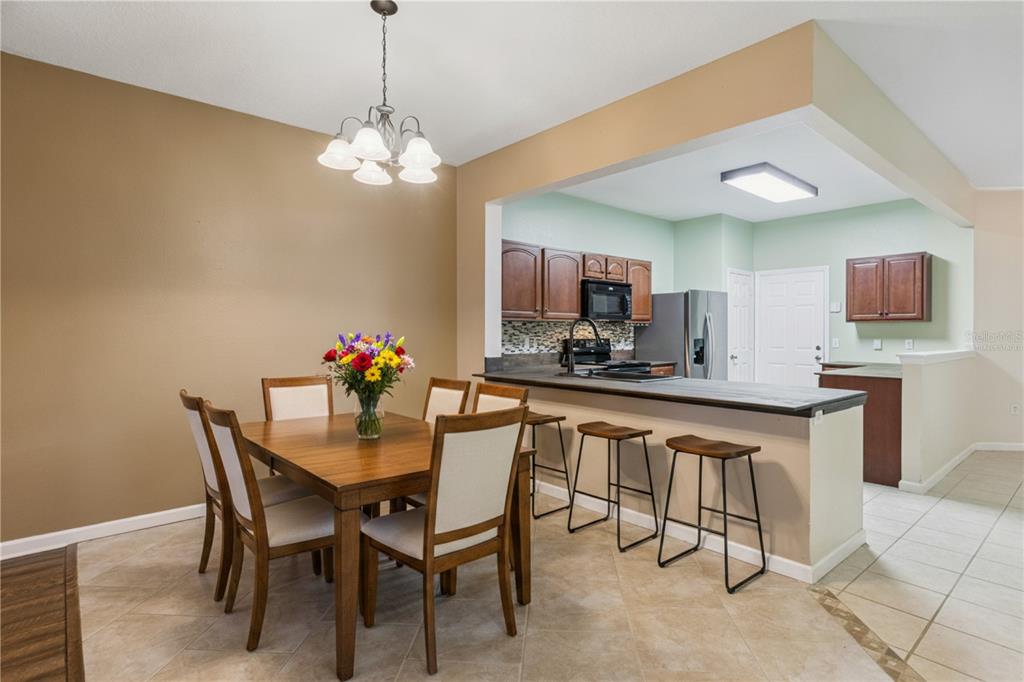 A dining area with a wooden table and chairs sits adjacent to an open kitchen — 2561 GALLIANO CIRCLE, WINTER PARK, FL