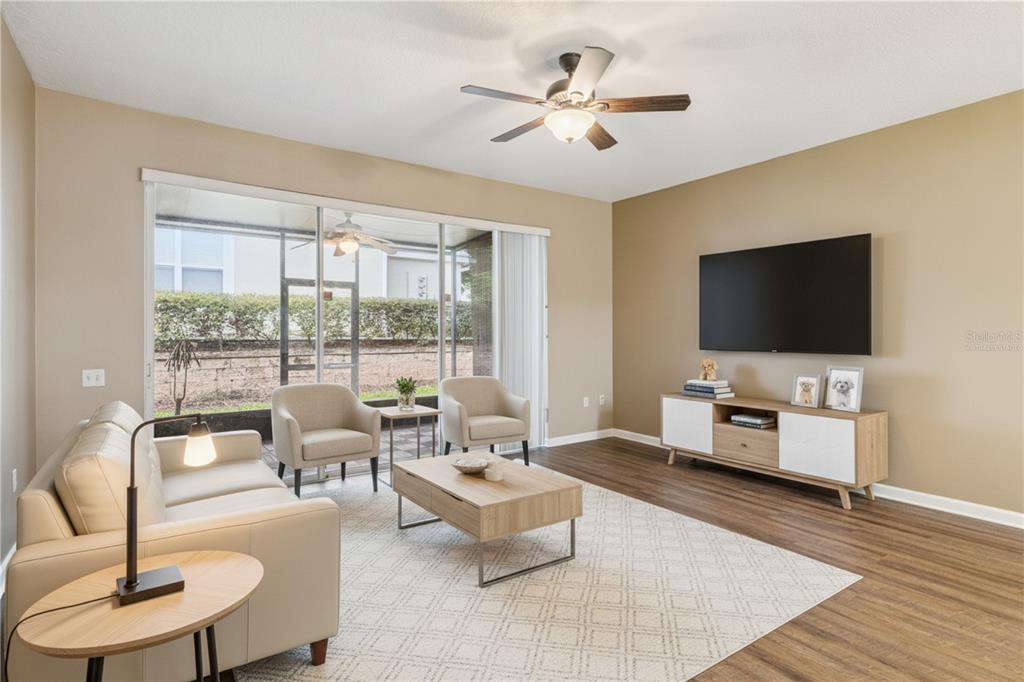 A living room features a beige sofa, two armchairs, a coffee table, and a wall-mounted television — 2561 GALLIANO CIRCLE, WINTER PARK, FL