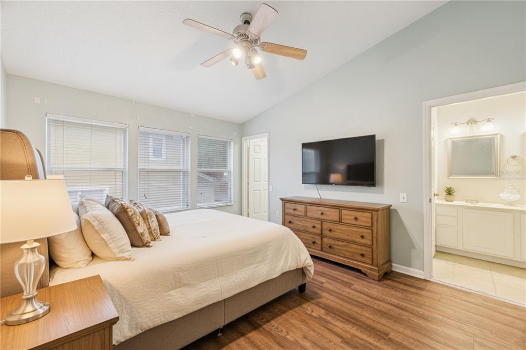 A bedroom features a bed, a wooden dresser with a wall-mounted television, and an attached bathroom — 2561 GALLIANO CIRCLE, WINTER PARK, FL