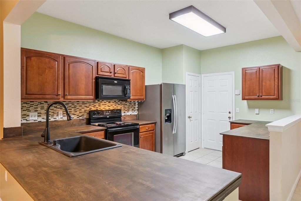 A kitchen features dark wood cabinets, a dark countertop, stainless steel appliances, and tile flooring — 2561 GALLIANO CIRCLE, WINTER PARK, FL