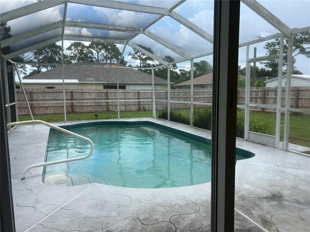 A screened-in swimming pool with a concrete deck sits in a fenced backyard — 3774 LORTON AVENUE, NORTH PORT, FL