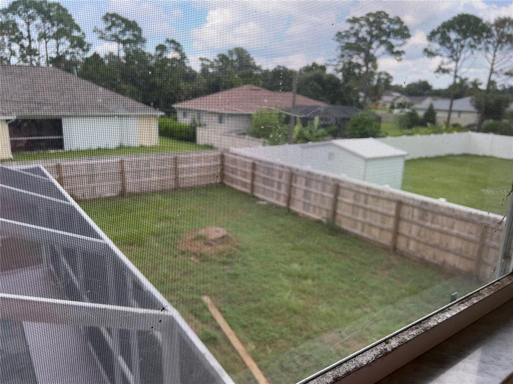 A view from a window looking out over a fenced backyard with a lawn — 3774 LORTON AVENUE, NORTH PORT, FL