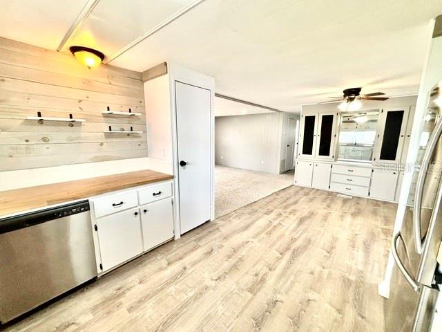 A kitchen with white cabinets, wood-look flooring, and a shiplap accent wall leads into a living area — 106 ALOHA TERRACE, PORT ORANGE, FL