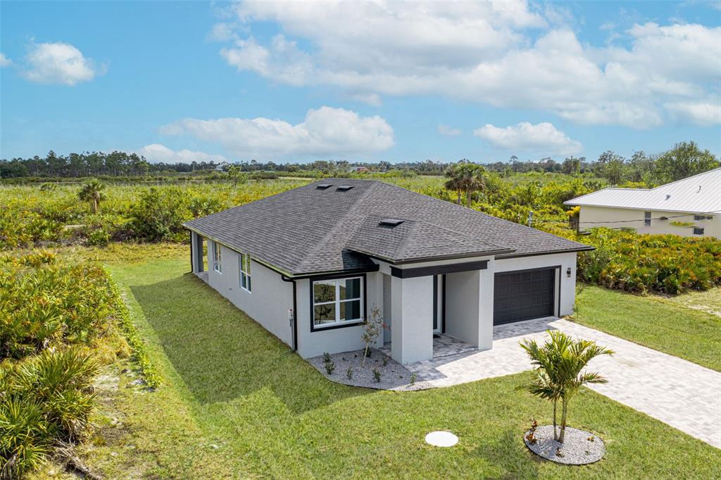An aerial view shows a single-story house with a gray exterior, dark roof, and garage — 384 BAYTREE DRIVE, ROTONDA WEST, FL