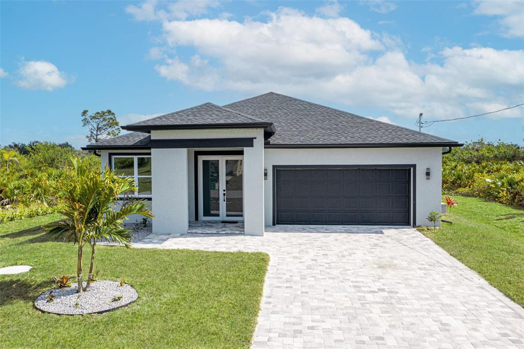 A modern single-story house with a gray roof, white stucco exterior, and a paved driveway — 384 BAYTREE DRIVE, ROTONDA WEST, FL