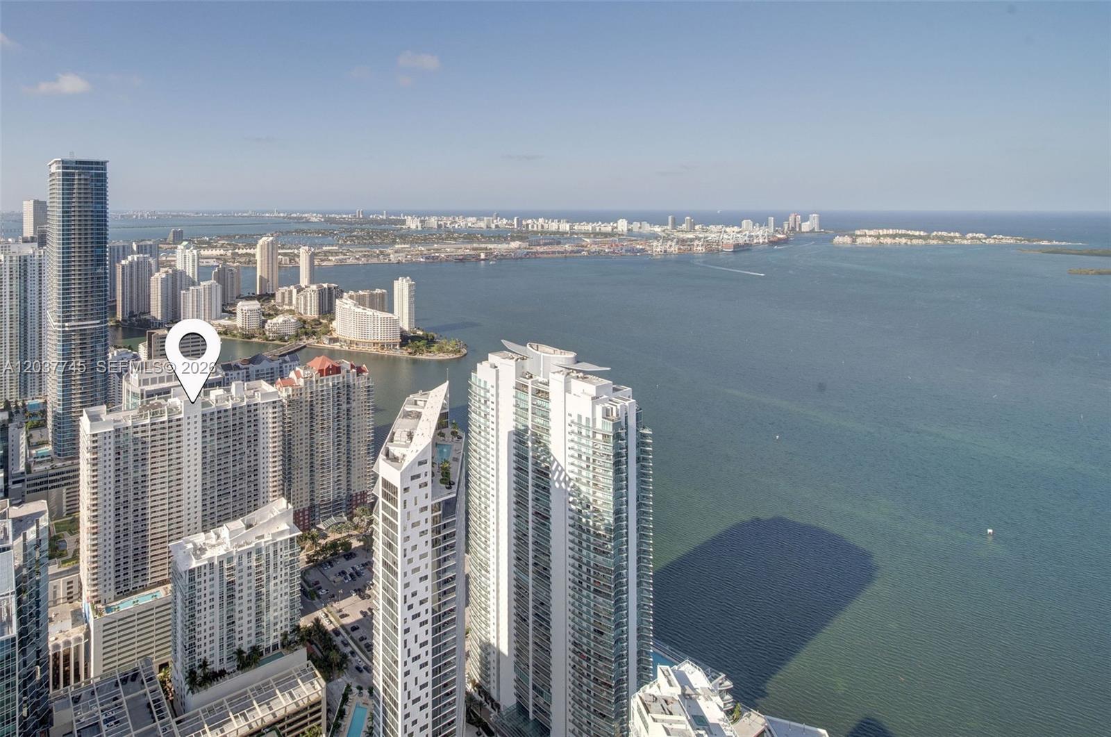 An aerial view shows high-rise residential towers overlooking a bay and a distant city skyline — 1200 Brickell Bay Dr # 3714, Miami FL 33131, MIAMI, FL