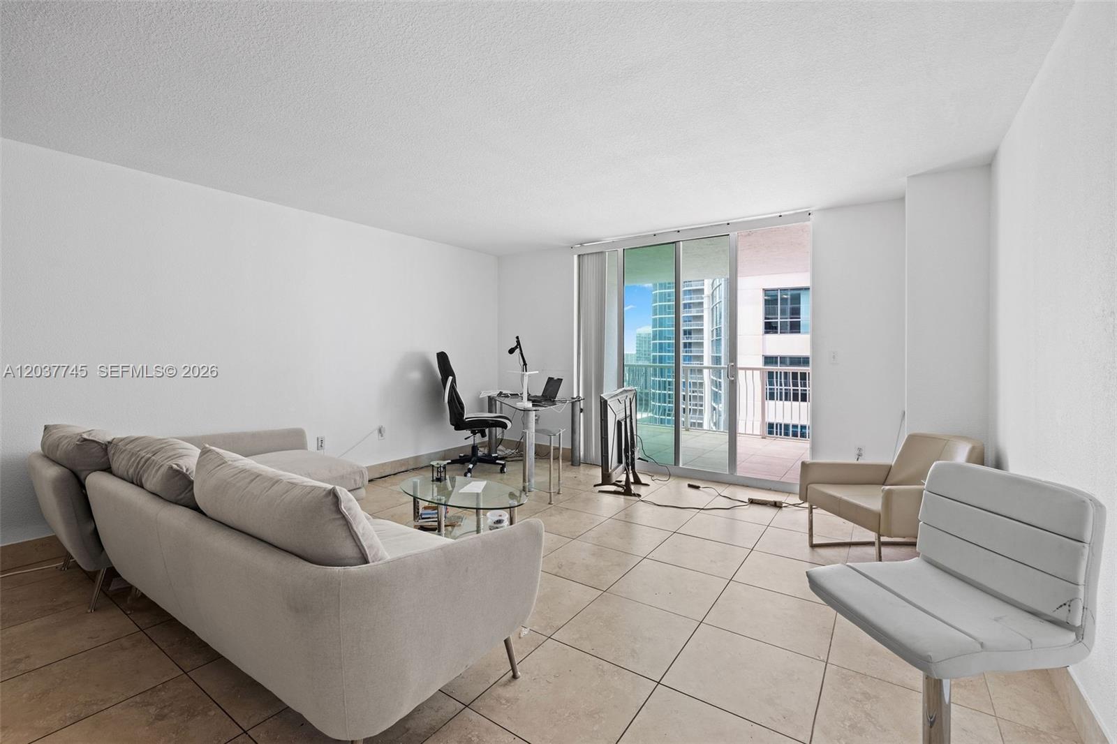 A living room with tile floors, a sofa, a desk, and a balcony with city views — 1200 Brickell Bay Dr # 3714, Miami FL 33131, MIAMI, FL