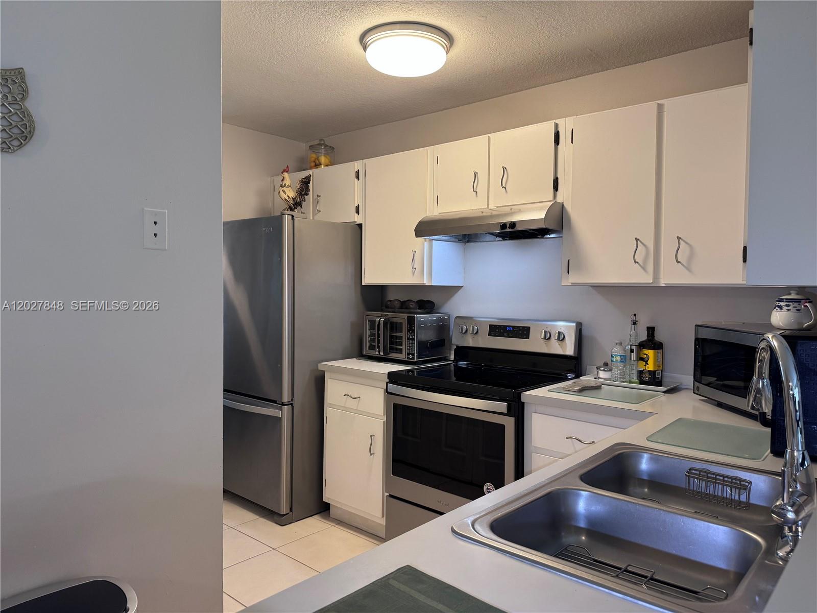 A kitchen features white cabinets, stainless steel appliances, and a double-basin sink — 12204 NW 36th Pl, Sunrise FL 33323, SUNRISE, FL
