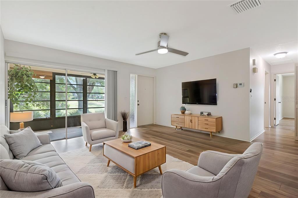 A living room features a grey sofa, wood coffee table, mirrored closet doors, and dining area — 2261 SHELLY DRIVE UNIT D, PALM HARBOR, FL