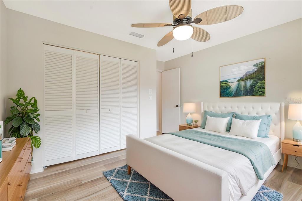 A bedroom features a white tufted bed, louvered closet doors, and a ceiling fan — 2261 SHELLY DRIVE UNIT D, PALM HARBOR, FL