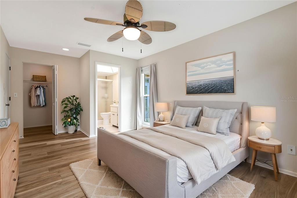 A bedroom with wood-look flooring, a ceiling fan, a bed, and an attached bathroom — 2261 SHELLY DRIVE UNIT D, PALM HARBOR, FL