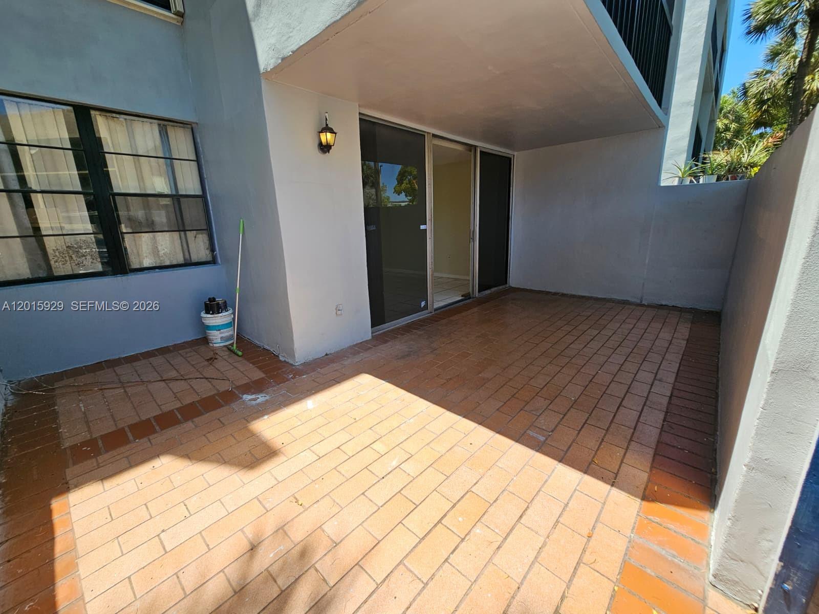 A ground-level patio features brick pavers, a sliding glass door, and a light fixture — 10825 SW 112th Ave # 103, Miami FL 33176, MIAMI, FL