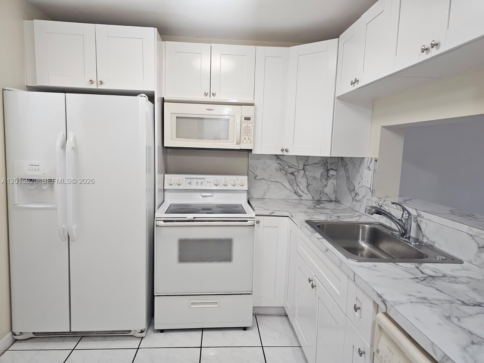 A kitchen features white cabinets, white appliances, and marble-patterned countertops and backsplash — 10825 SW 112th Ave # 103, Miami FL 33176, MIAMI, FL