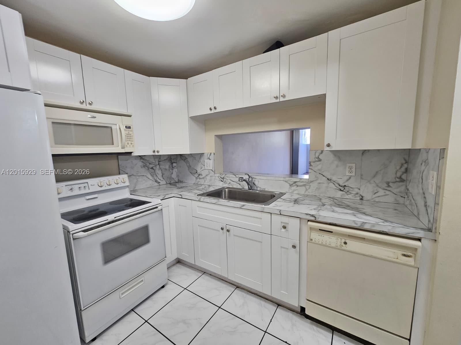 A kitchen features white cabinets, marble-patterned countertops, a stainless steel sink, and white appliances — 10825 SW 112th Ave # 103, Miami FL 33176, MIAMI, FL
