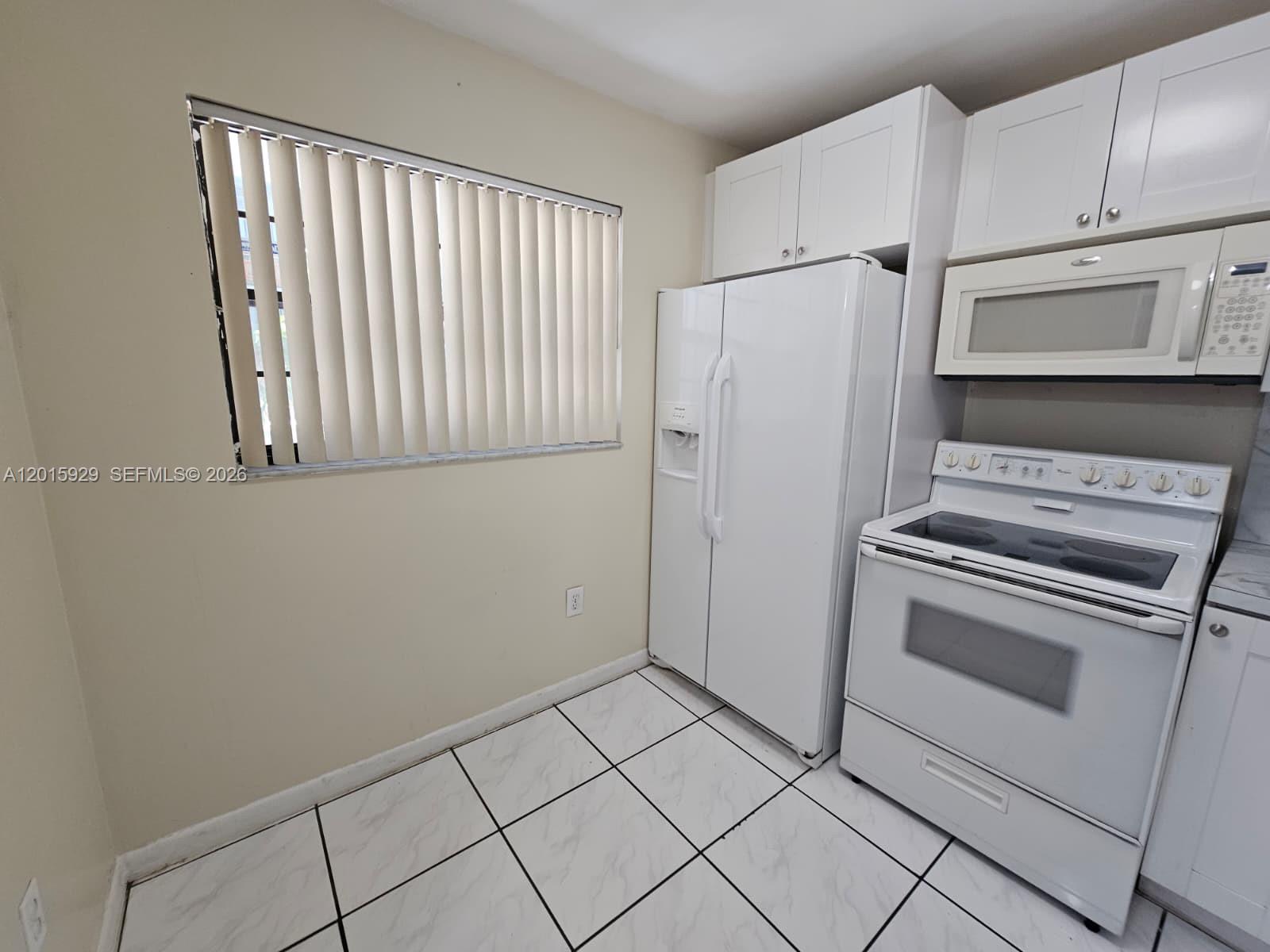 A kitchen features white appliances, white cabinets, and white tile flooring with dark grout — 10825 SW 112th Ave # 103, Miami FL 33176, MIAMI, FL