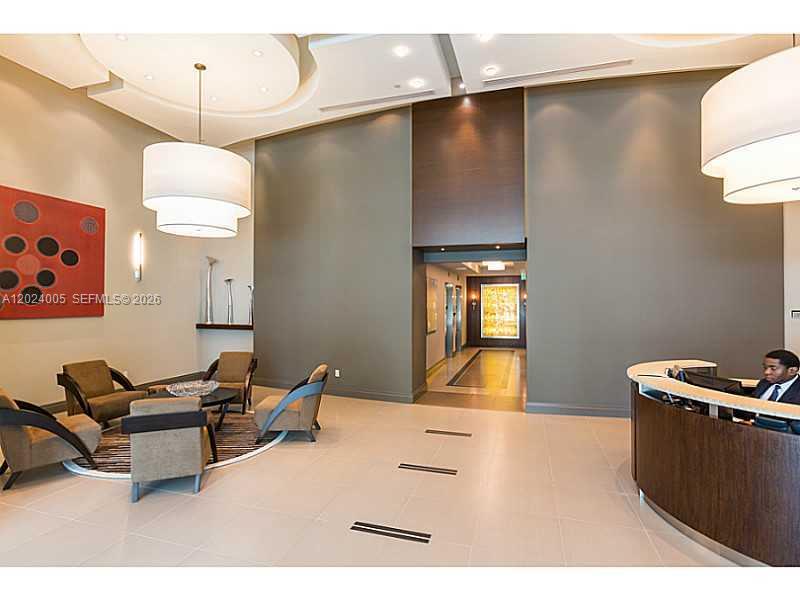 A modern building lobby features a reception desk, seating area, and large pendant light fixtures — 2525 SW 3 AV # 1006, Miami FL 33129, MIAMI, FL