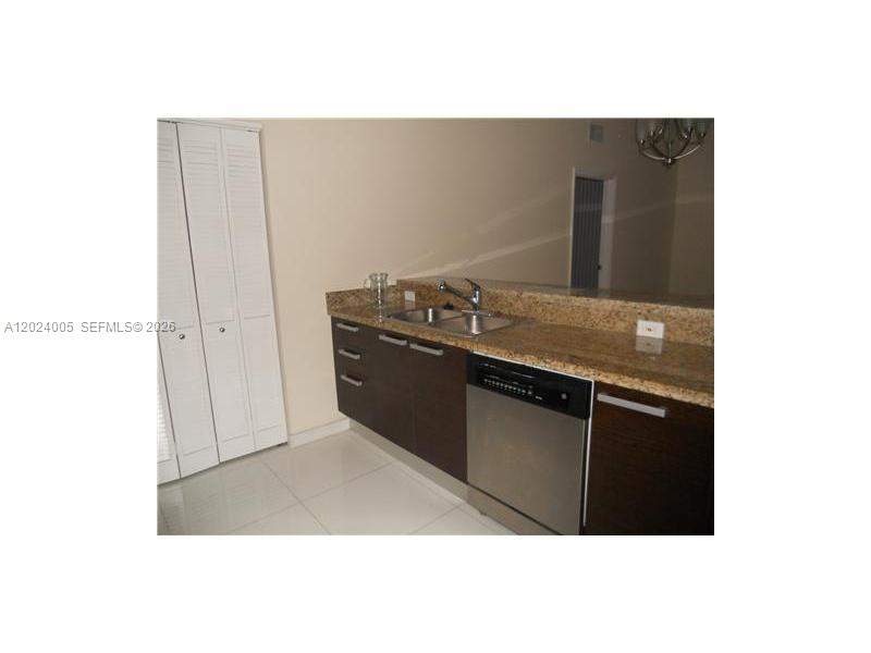 A kitchen features dark wood cabinets, granite countertops, a stainless steel dishwasher, and white flooring — 2525 SW 3 AV # 1006, Miami FL 33129, MIAMI, FL