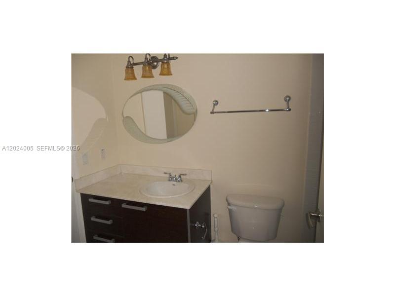 A bathroom features a dark wood vanity, a round mirror, and a wall-mounted towel bar — 2525 SW 3 AV # 1006, Miami FL 33129, MIAMI, FL