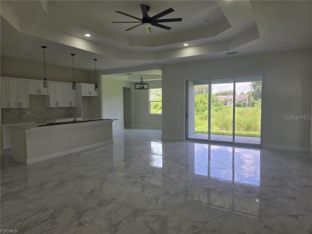 A kitchen and living area with white cabinets, a breakfast bar, and marble-look tile flooring — 3852 HOPEVALE STREET, FORT MYERS, FL