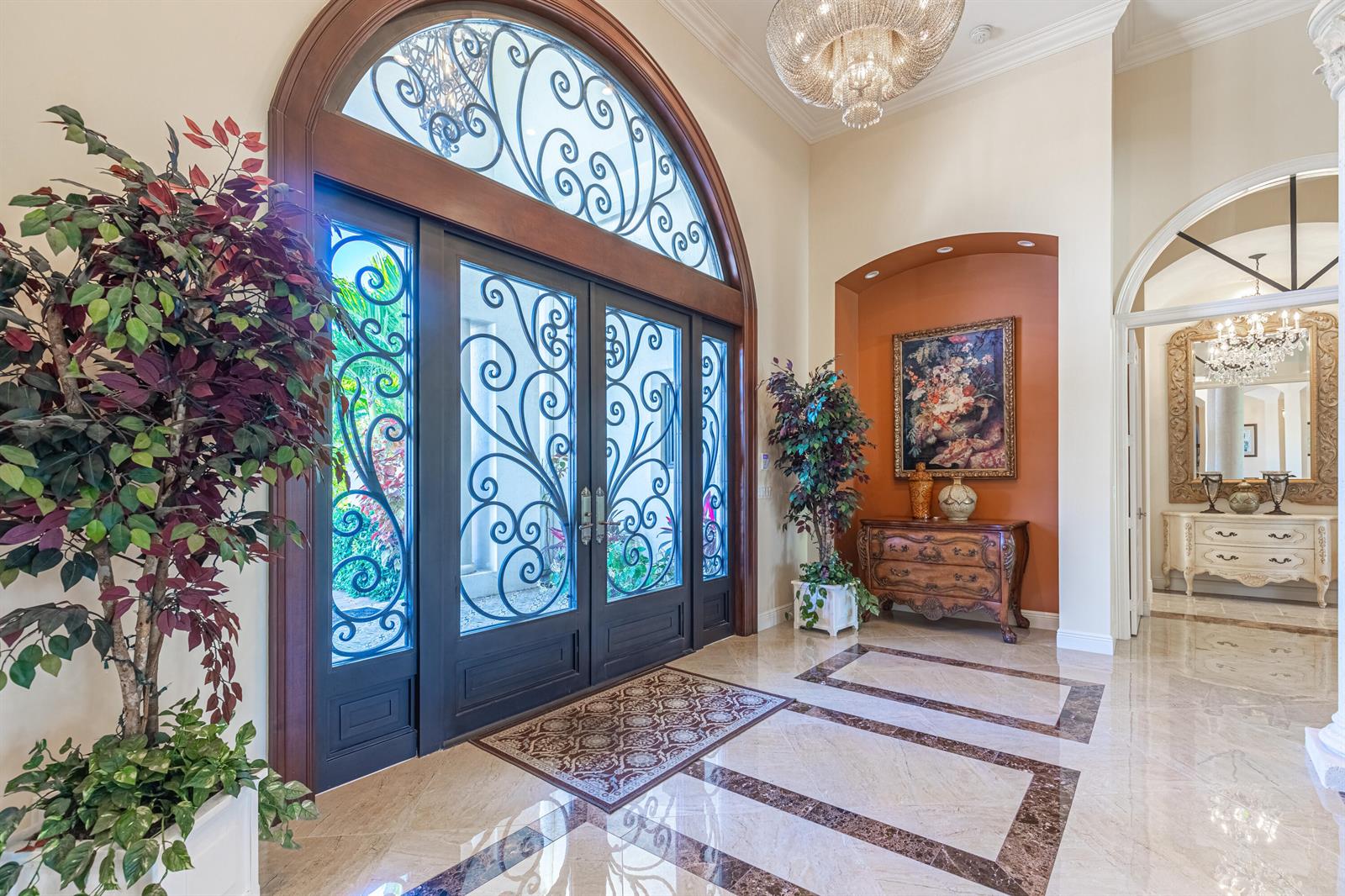 A grand foyer features a large arched iron door, marble flooring, and a crystal chandelier — 2943 B Road, FL 33470, FL