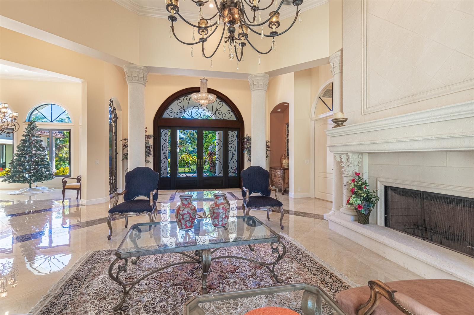 A grand foyer features a large chandelier, marble floors, a fireplace, and arched glass doors — 2943 B Road, FL 33470, FL