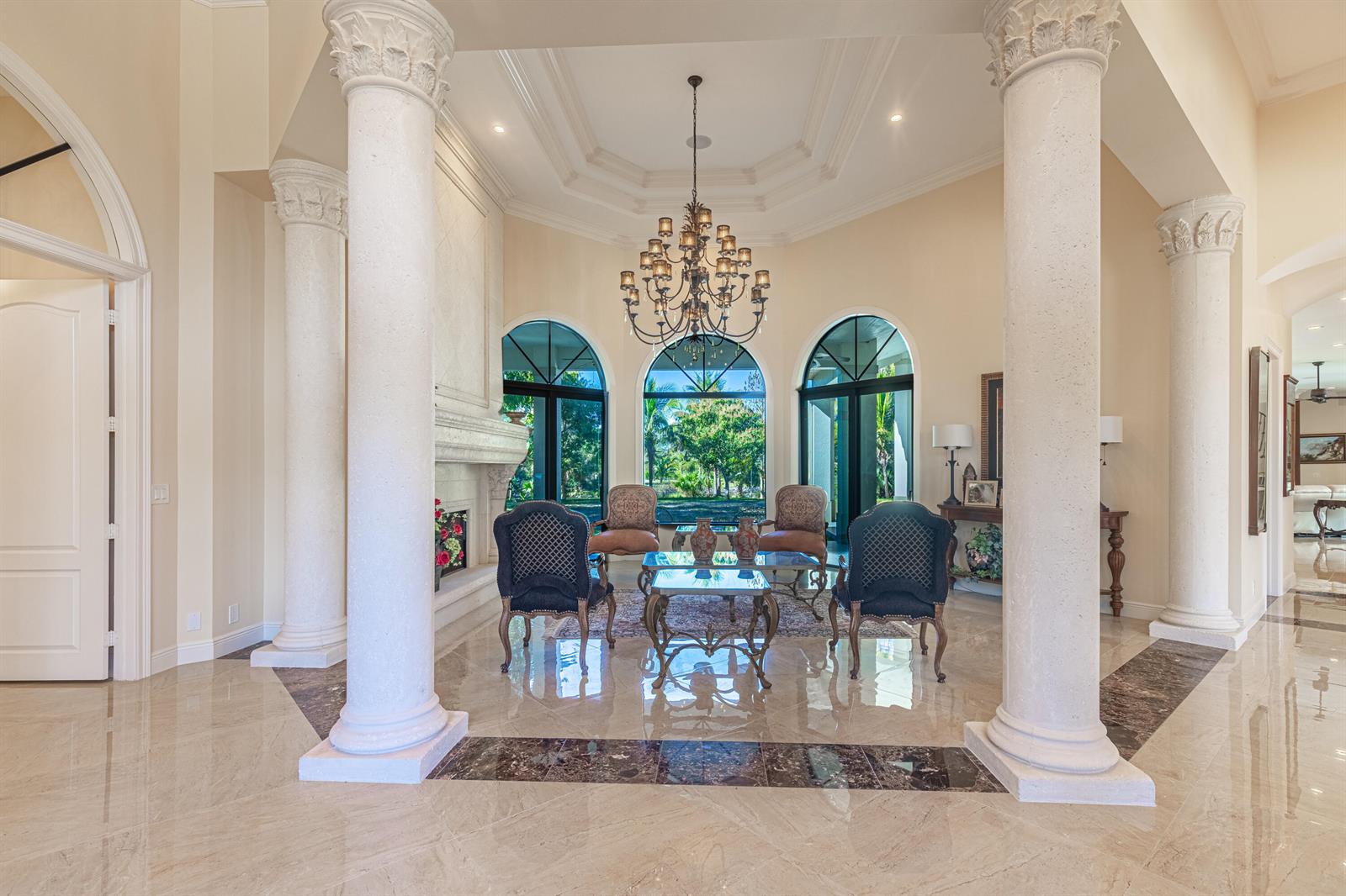 A formal living room features tall columns, a crystal chandelier, and large arched windows — 2943 B Road, FL 33470, FL