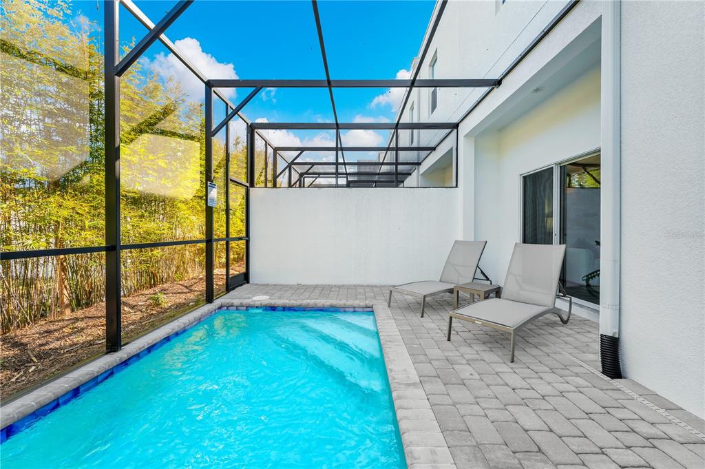 A small rectangular swimming pool sits on a paved patio enclosed by a screened lanai — 396 FAMAGUSTA DRIVE, DAVENPORT, FL