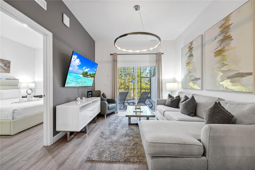 A living room features a grey sectional sofa, a white media console, and a sliding door — 396 FAMAGUSTA DRIVE, DAVENPORT, FL