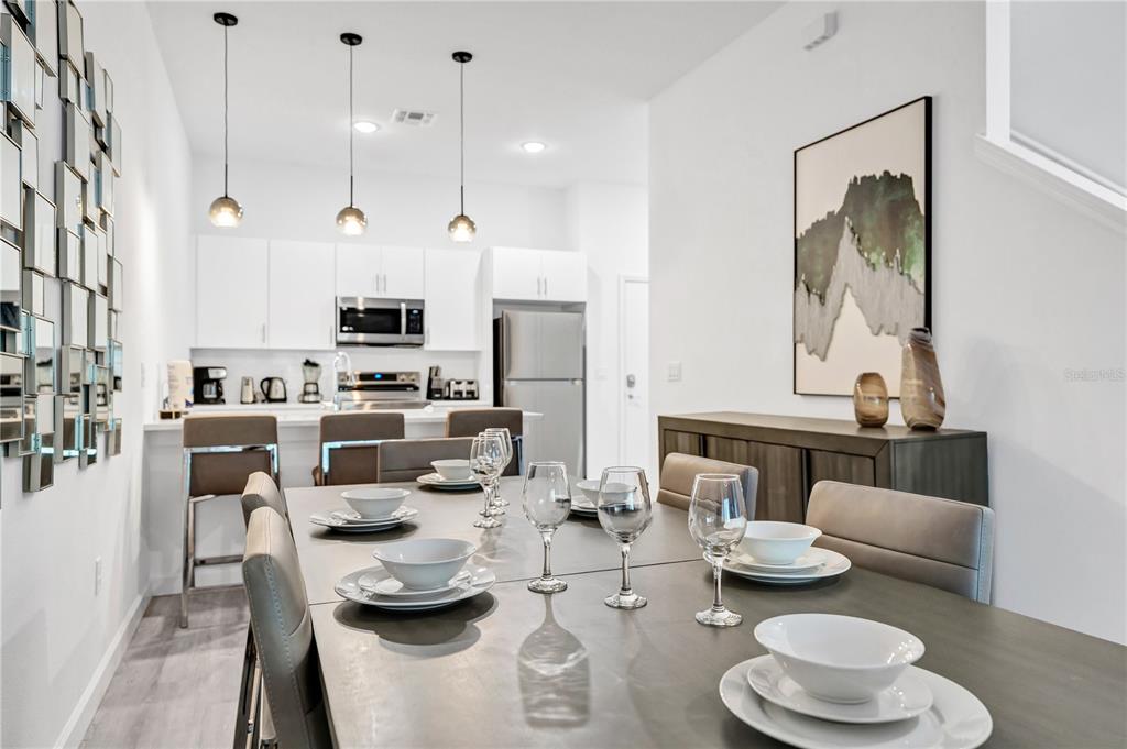 A dining area with a table and chairs sits in front of a modern kitchen — 396 FAMAGUSTA DRIVE, DAVENPORT, FL