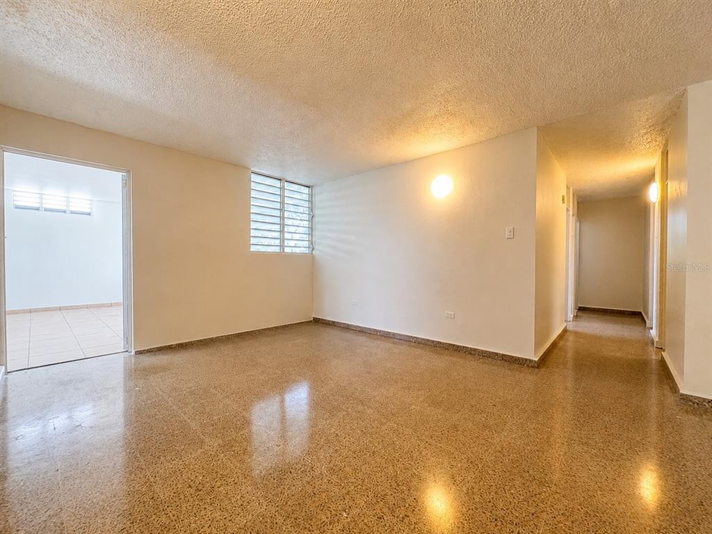 An empty room with light-colored walls, a window, and polished speckled flooring — #1 ST. URB. VILLA ARRIETA 1ST FLOOR UNIT C-51, BAYAMON, PR