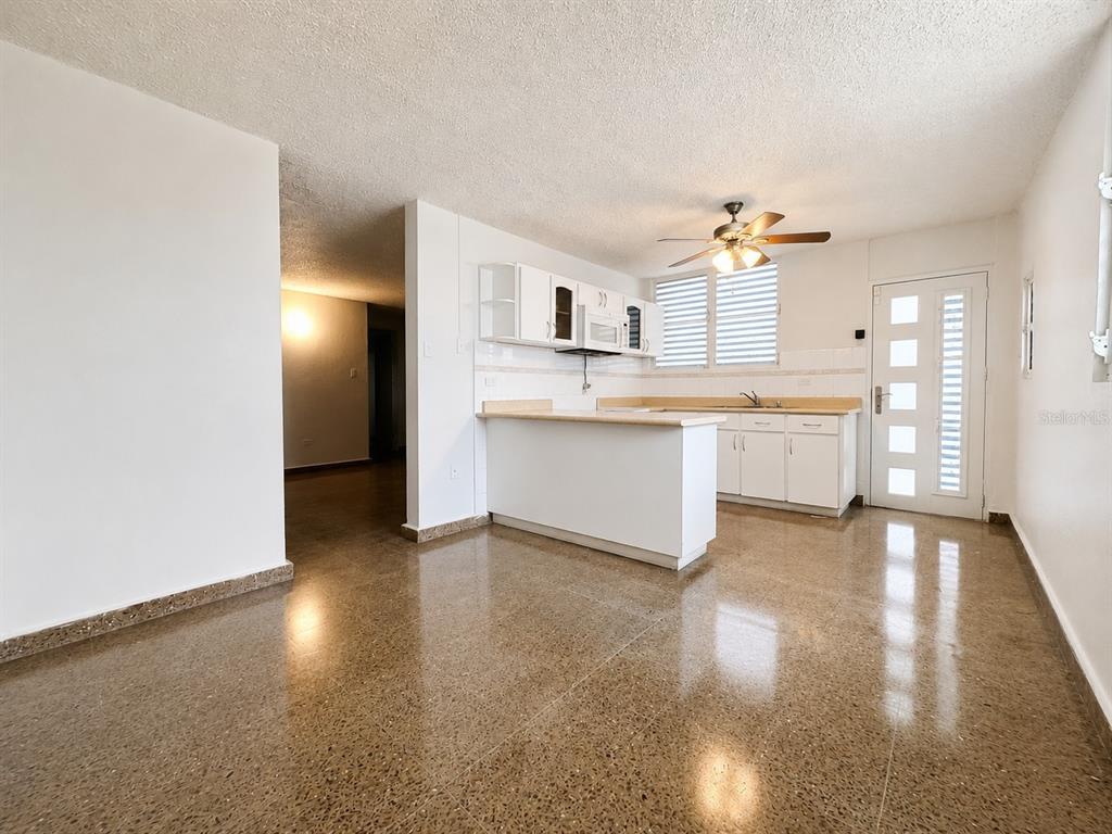 A kitchen with white cabinets, a breakfast bar, and polished terrazzo flooring — #1 ST. URB. VILLA ARRIETA 1ST FLOOR UNIT C-51, BAYAMON, PR