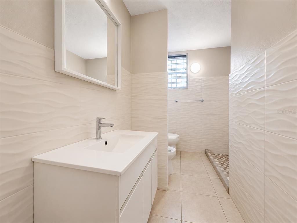 A modern bathroom features a white vanity, a mirror, and a tiled walk-in shower — #1 ST. URB. VILLA ARRIETA 1ST FLOOR UNIT C-51, BAYAMON, PR